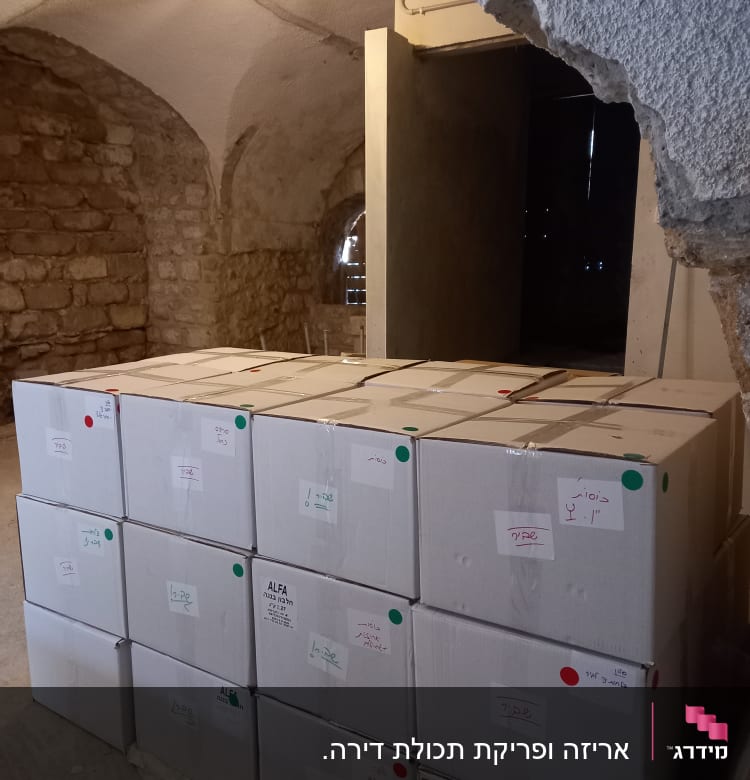 קופסאות קרטון מסודרות בערימה במחסן עם קירות אבן